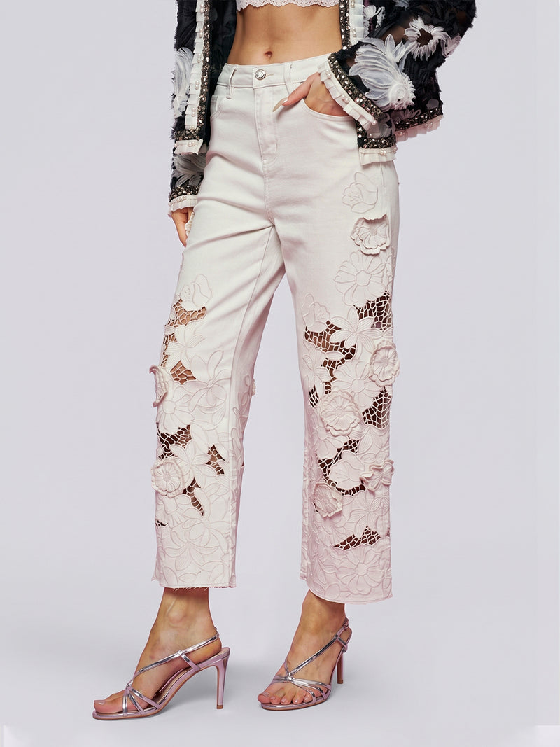 A person wearing Social Queen’s Floral Cutout High-Rise Jean, paired with a black and white jacket and metallic high-heeled sandals.