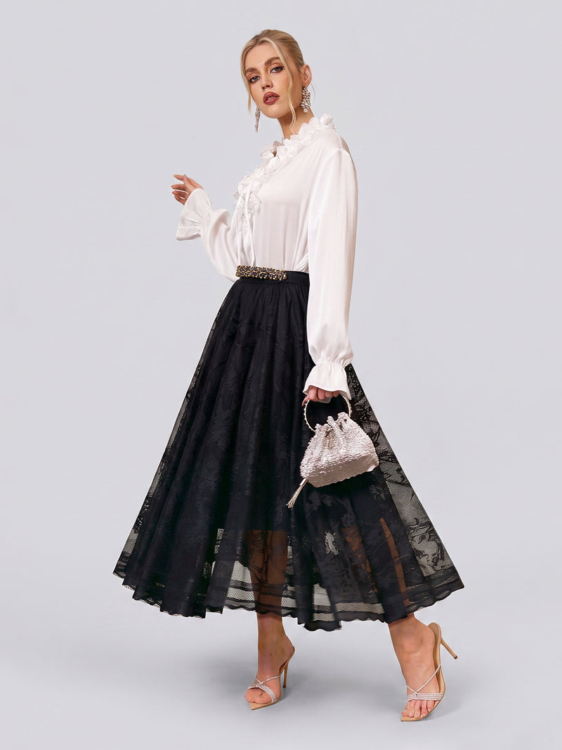 A woman in a white long-sleeve blouse and the Social Queen Jacquard Lace A-Line Midi Skirt, holding a small silver handbag and wearing strappy heels, stands against a plain light background. This elegant skirt features a high-waist A-line midi silhouette for timeless sophistication, making it an ideal choice for wedding guests.