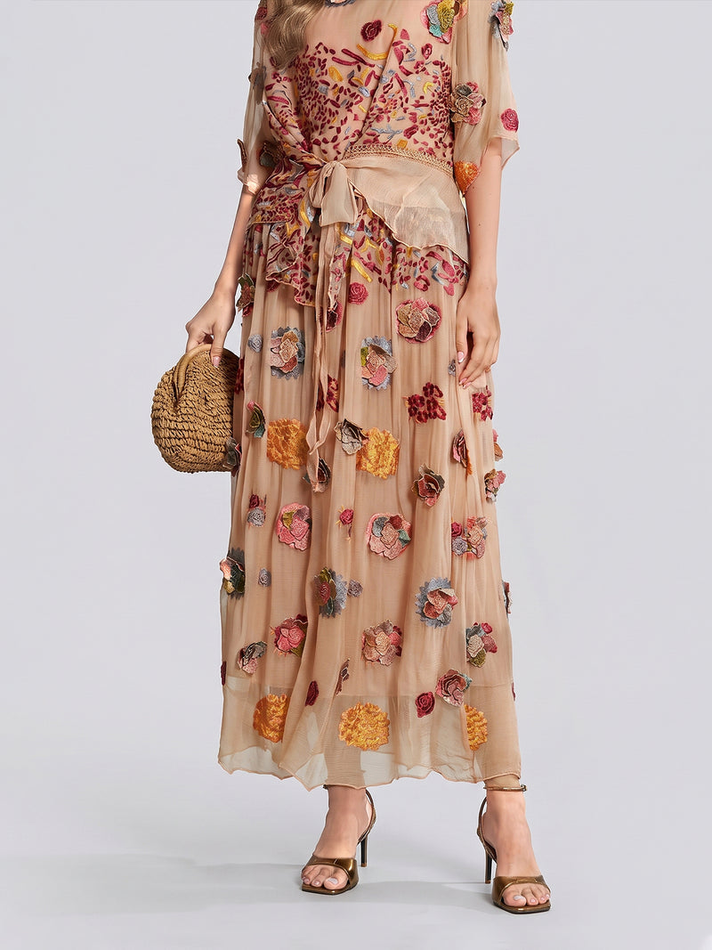 A woman styled in the Social Queen Floral Embroidered Silk A-Line Skirt, featuring a sheer, high-waisted beige silhouette with delicate floral embroidery, paired with a woven handbag and strappy heels.