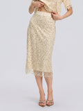 A woman stands against a plain background wearing the Social Queen Crystal Beaded Fringe Midi Skirt in beige, styled with a matching top. She poses with one hand lifting the shirt hem and the other resting on her hip.