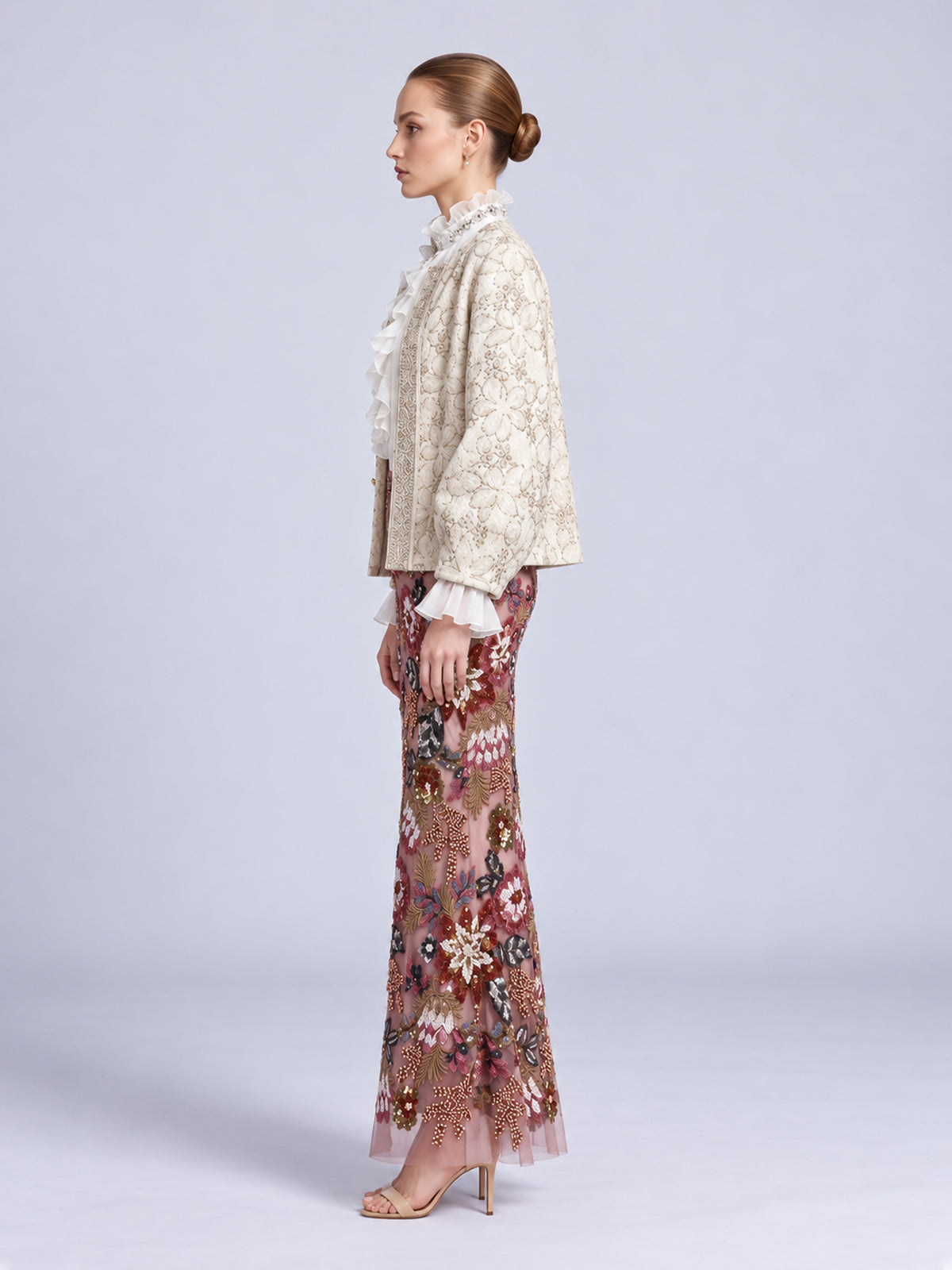 Model wearing a Social Queen Floral Appliqué Embroidered Jacket over a ruffled blouse and a long, floral-embroidered skirt with sequins.