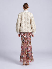 Back view of a person wearing a cream-colored Floral Appliqué Embroidered Jacket by Social Queen over a floor-length sheer skirt with colorful floral embroidery and beadwork.