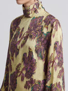 Close-up of a person wearing the Social Queen Art Floral Jacquard Maxi Dress, featuring long sleeves, a high neckline, and a vivid purple and green floral pattern on yellow, crafted with the elegant detail characteristic of viscose jacquard.