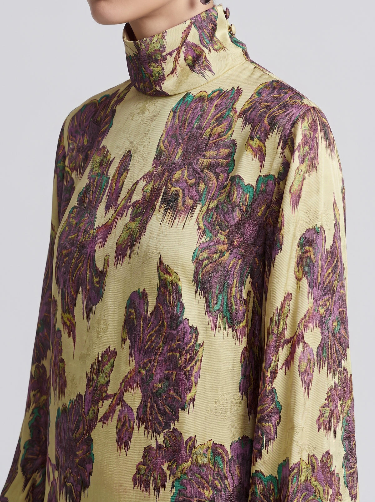 Close-up of a person wearing the Social Queen Art Floral Jacquard Maxi Dress, featuring long sleeves, a high neckline, and a vivid purple and green floral pattern on yellow, crafted with the elegant detail characteristic of viscose jacquard.