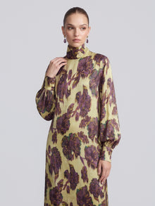 A person wearing the Social Queen Art Floral Jacquard Maxi Dress, featuring long sleeves, a high neckline, and a yellow base with a purple floral jacquard pattern, stands against a plain light background.