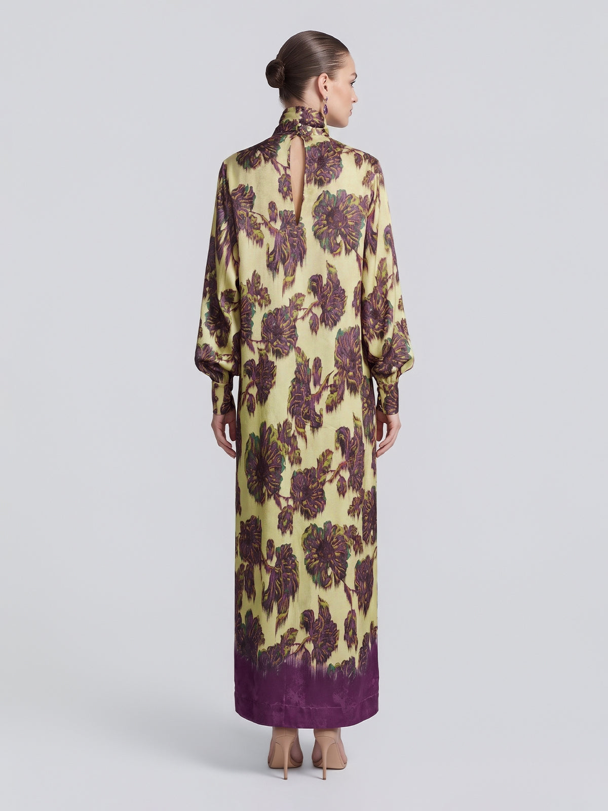 A woman with her hair in a bun models the Social Queen Art Floral Jacquard Maxi Dress, a long-sleeved, floor-length piece featuring purple accents and crafted from luxurious viscose jacquard, shown from the back against a plain light background.
