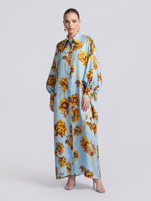 A model wears a light blue long-sleeved Social Queen Floral Print Maxi Shirtdress (Tie Included) featuring a yellow floral pattern in a relaxed silhouette.