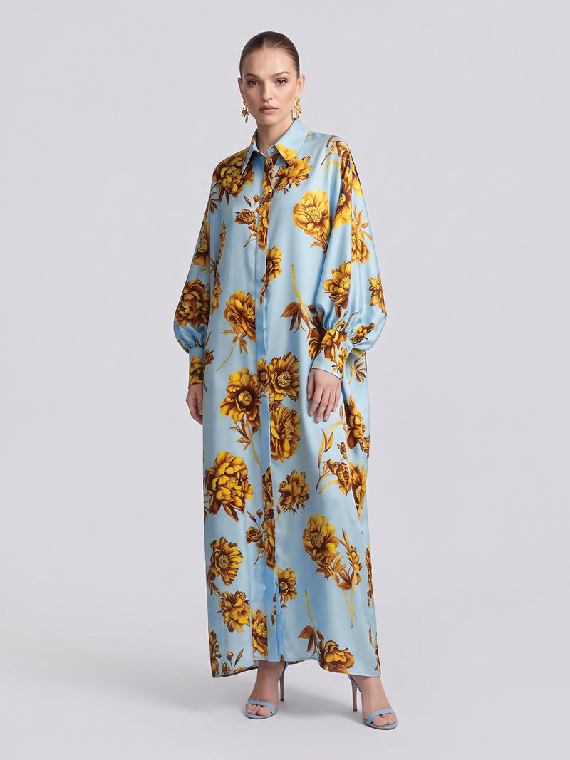 A model wears a light blue long-sleeved Social Queen Floral Print Maxi Shirtdress (Tie Included) featuring a yellow floral pattern in a relaxed silhouette.