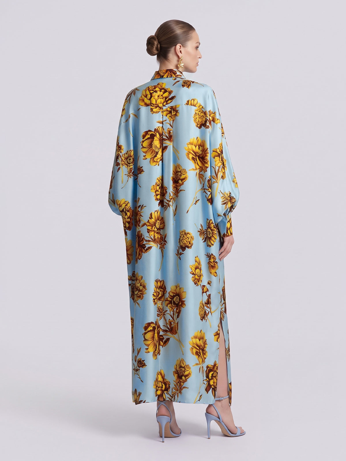 Back view of a light blue Floral Print Maxi Shirtdress (Tie Included) by Social Queen, featuring a yellow floral print and side slits, worn with light blue heels in a relaxed silhouette.
