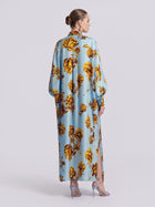Back view of a light blue Floral Print Maxi Shirtdress (Tie Included) by Social Queen, featuring a yellow floral print and side slits, worn with light blue heels in a relaxed silhouette.