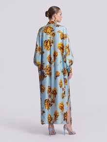 Back view of a light blue Floral Print Maxi Shirtdress (Tie Included) by Social Queen, featuring a yellow floral print and side slits, worn with light blue heels in a relaxed silhouette.