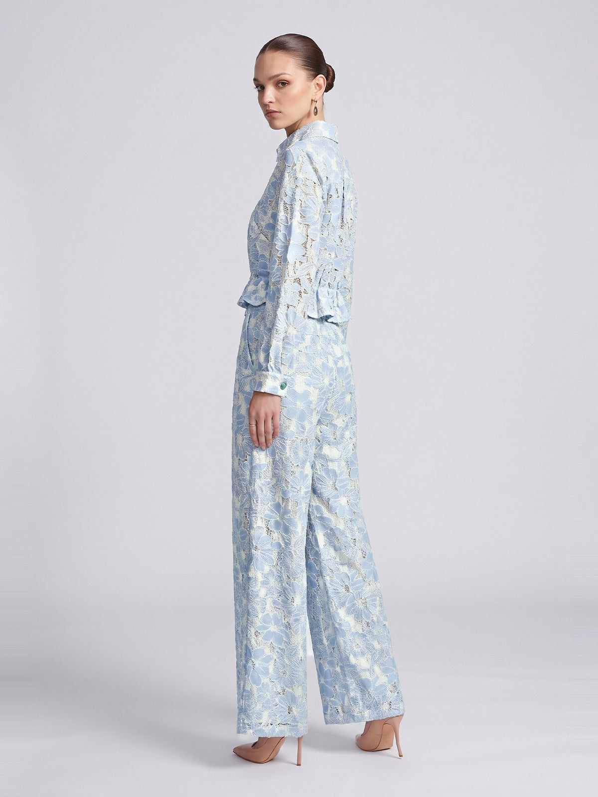 A woman wears a light blue and white floral openwork lace button-down shirt and matching Social Queen Floral Lace Wide-Leg Pants.