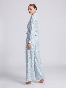 A woman wears a light blue and white floral openwork lace button-down shirt and matching Social Queen Floral Lace Wide-Leg Pants.
