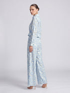 A person viewed from the side, wearing a light blue Floral Lace Cropped Jacket and matching wide-leg trousers.