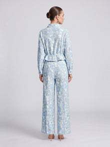 Back view of a person wearing a light blue, floral lace Floral Lace Cropped Jacket and matching wide-leg trousers.