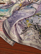 A close-up of the Social Queen Art Silk Print Scarf, featuring vibrant purple, pink, and yellow hues on a wooden surface—a stylish accessory for any wedding guest.