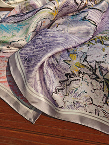 A close-up of the Social Queen Art Silk Print Scarf, featuring vibrant purple, pink, and yellow hues on a wooden surface—a stylish accessory for any wedding guest.
