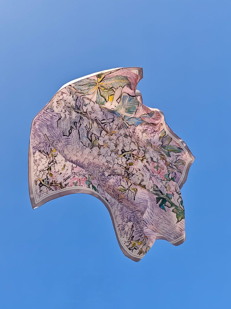 A Social Queen Art Silk Print Scarf, featuring a multicolored abstract floral pattern like an oil painting, is fluttering against the clear blue sky.