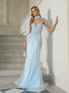 A woman stands on stairs wearing the Social Queen Artisanal Beaded Fringe High-Neck Gown, a fitted light blue evening dress with sheer panels, cape sleeves, fishtail hem, matching choker, and holding a small silver purse.