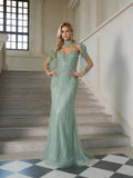A woman stands on indoor stairs wearing the Artisanal Beaded Fringe High-Neck Gown by Social Queen, paired with statement earrings—an exquisite choice for any formal event.