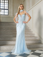 A woman in the Social Queen Artisanal Beaded Fringe High-Neck Gown poses on a marble staircase inside an elegant, high-ceilinged space with tall windows.