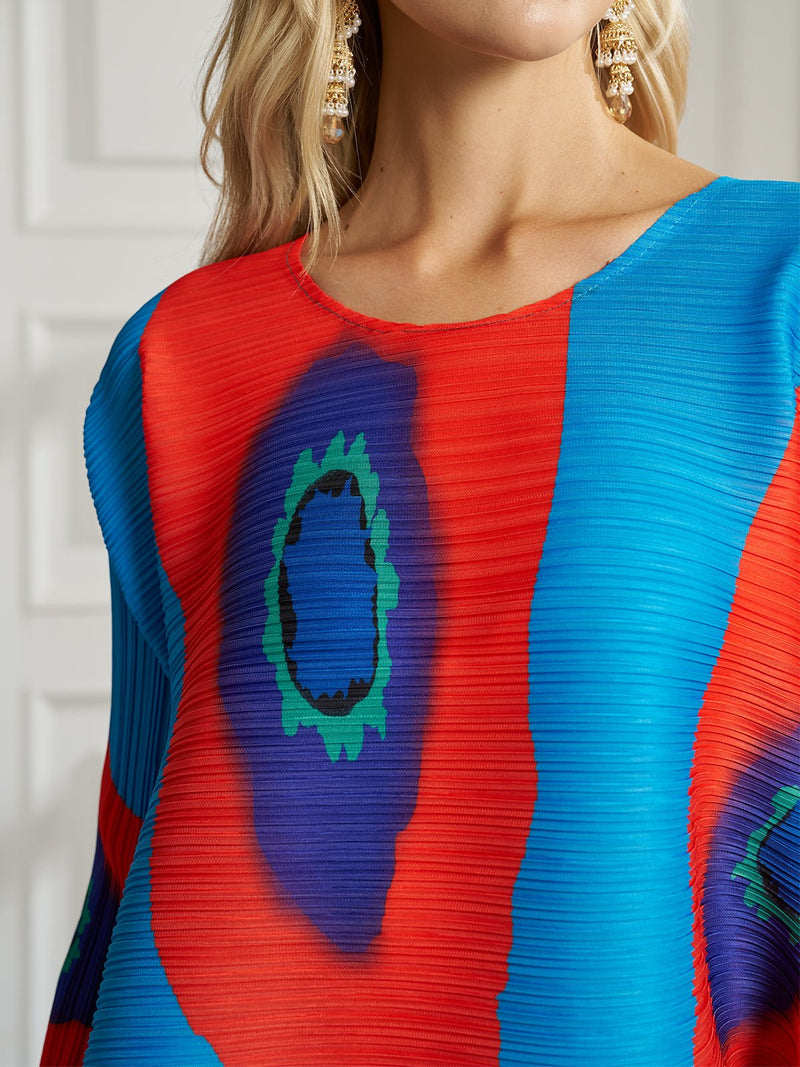 A woman wears Social Queen’s Artistic Print Plissé A-Line Dress—an abstract, multicolored piece paired with gold drop earrings, ideal for chic resort style.
