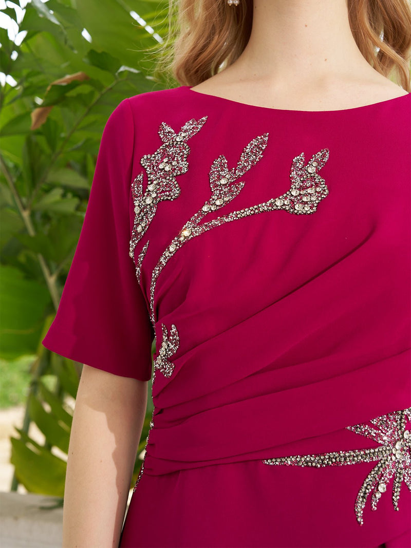 A woman wearing the Social Queen Asymmetric Beaded Mermaid Slit Dress stands before lush green foliage.