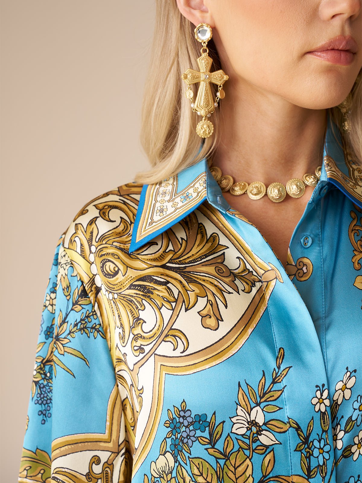 Woman shown from the shoulder up wearing the Social Queen Baroque Engineered-Print Silk Shirt, accessorized with a gold medallion necklace and ornate gold cross-shaped earrings.