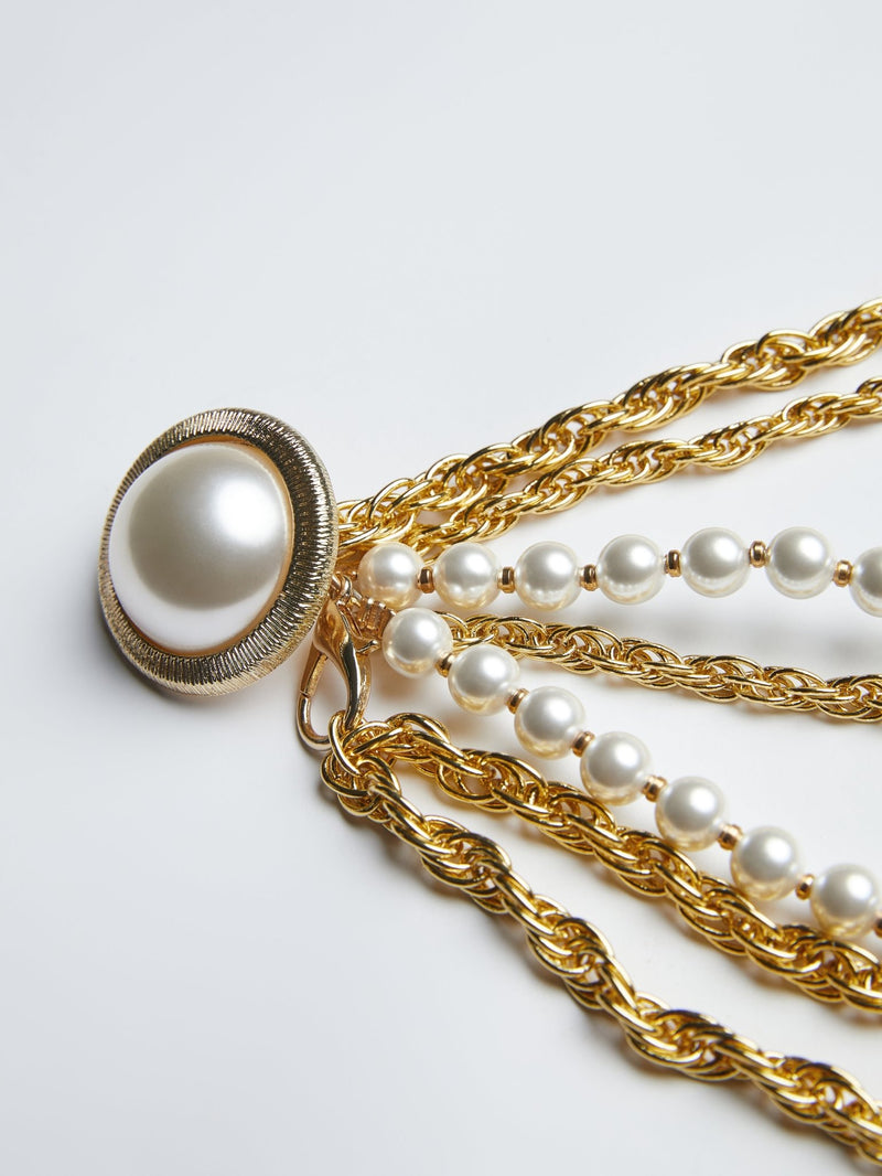 Close-up of the Social Queen Baroque Pearl Chain Belt, featuring a large round pearl set in gold and layered gold chains accented with strands of baroque pearls.