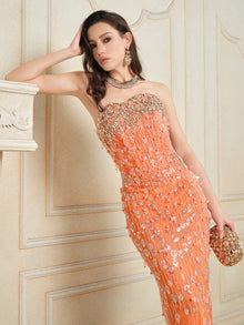 A woman poses indoors wearing the Social Queen Beaded Crystal Strapless Gown, styled with a matching clutch, elegant jewelry, and wavy side-swept hair.