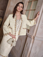 A woman stands indoors wearing the Social Queen Beaded Floral Embroidered Tweed Jacket in cream, paired with a matching handbag and layered necklaces.
