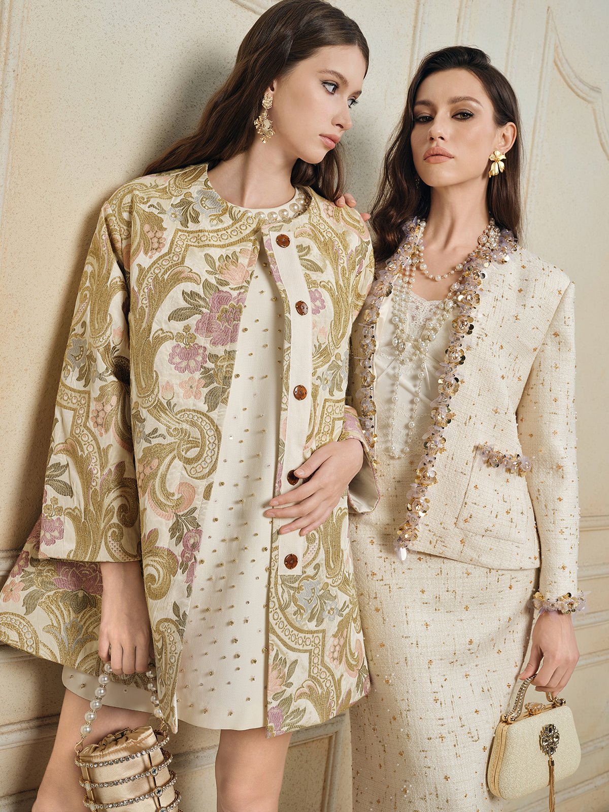 Two women wearing Social Queen's Beaded Floral Embroidered Tweed Jacket in cream and gold, styled with jewelry and handbags, stand against a light-colored wall.