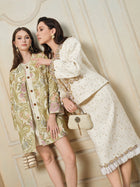 Two women pose indoors in ornate outfits; one wears a patterned coat, while the other showcases Social Queen's Beaded Floral Embroidered Tweed Skirt and carries a small clutch handbag.