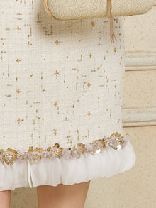 A close-up of the Social Queen Beaded Floral Embroidered Tweed Skirt, featuring gold and 3D floral embellishments at the hem, with part of a beige handbag visible.