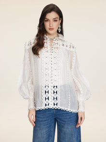 A woman in the Social Queen Beaded Geometric Lace Blouse with lantern sleeves and hand-crocheted details pairs it with blue jeans, standing against a plain beige background.