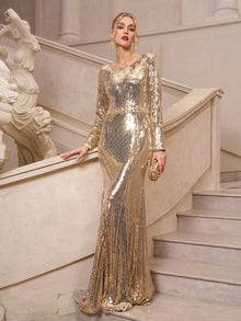 A woman in the Social Queen Beaded Gold-Accent Crystal Gown stands on a stone staircase, holding a small gold clutch, with a classical statue in the background.