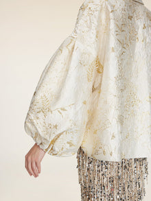 Wearing the Social Queen Beaded Jacquard Lantern Sleeve Jacket paired with a skirt adorned in metallic and sequin fringe.
