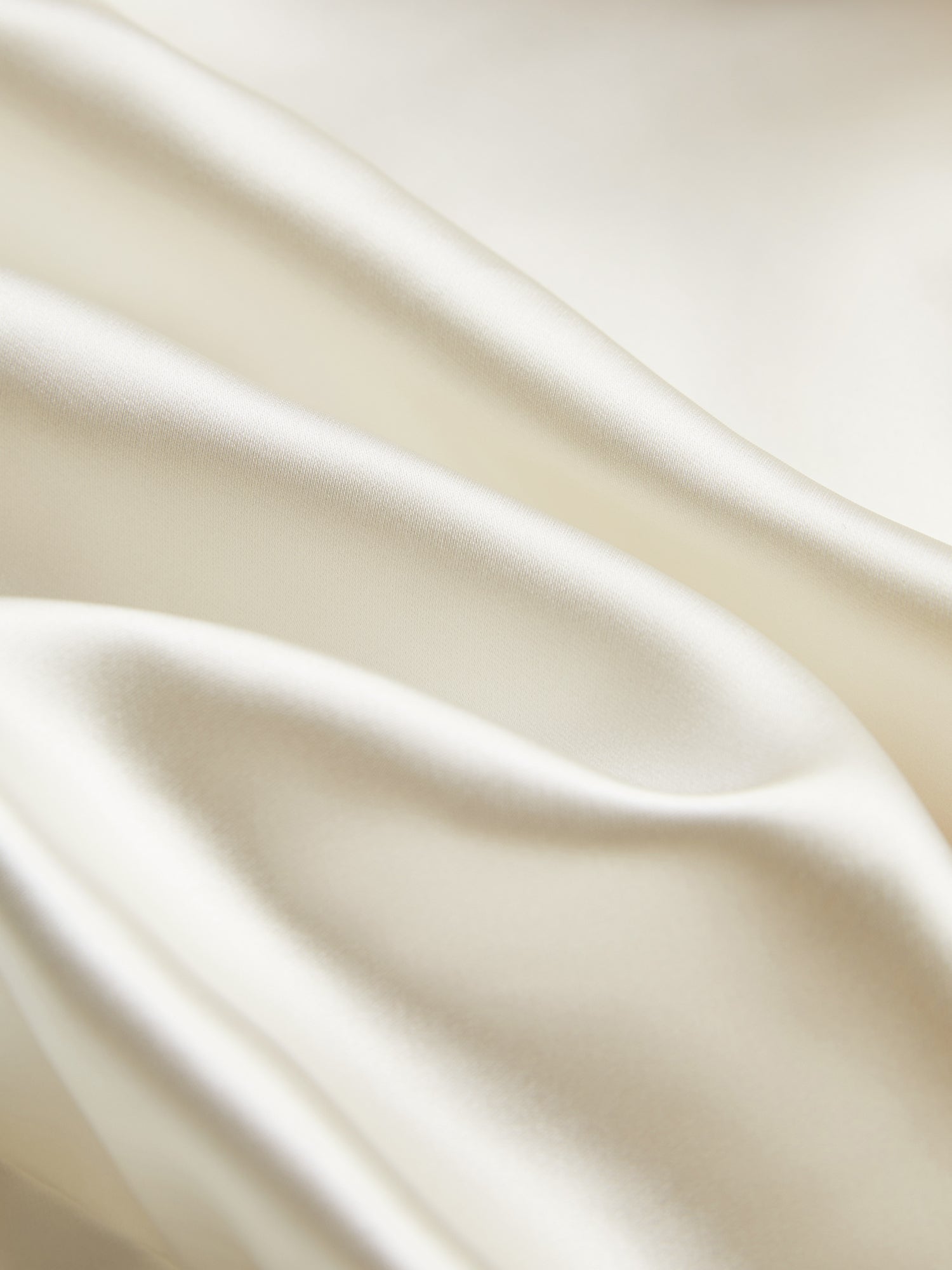 Close-up of the Beaded Ruffle Satin Blouse by Social Queen, featuring smooth off-white satin with soft folds, a subtle sheen, and delicate hand-stitched ruffles.