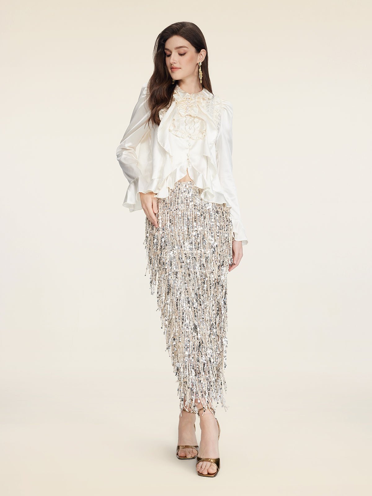 A woman stands against a plain background wearing the Beaded Ruffle Satin Blouse by Social Queen, featuring hand-stitched ruffles.