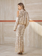 A woman stands indoors wearing the Social Queen Beaded Sequin Cold Shoulder Top, styled with high heels and facing away from the camera against a beige tiled wall.