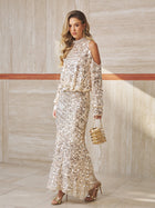 A woman in the Social Queen Beaded Sequin Cold Shoulder Top, gold heeled sandals, and a gold clutch stands against a marble wall.