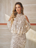 A woman with long, wavy blonde hair wears the Social Queen Beaded Sequin Cold Shoulder Top, posing indoors against a beige stone wall and looking at the camera with a neutral expression.