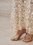 A person wearing gold strappy high-heeled sandals and the Social Queen Beaded Sequin Mermaid Elastic Skirt stands on a tiled floor.