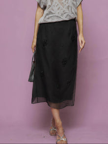 A person wears the Social Queen Beaded Silk Organza Midi Skirt, styled with a grey short-sleeve knit top. Only the lower half is visible against a mauve background.
