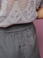 Close-up of a person wearing Social Queen's Beaded Silk Organza Midi Skirt, featuring delicate embroidery, standing against a pink background.