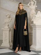 A woman stands in an ornate room wearing the Social Queen Beaded Tulle Caftan Cape Dress, holding a small decorated handbag and surrounded by classical statues.