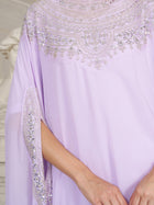A person wearing the Social Queen Beaded Tulle Caftan Cape Dress, adorned with silver sequins and beads on chiffon, featuring intricate embroidery and detailed neckline and sleeve patterns.