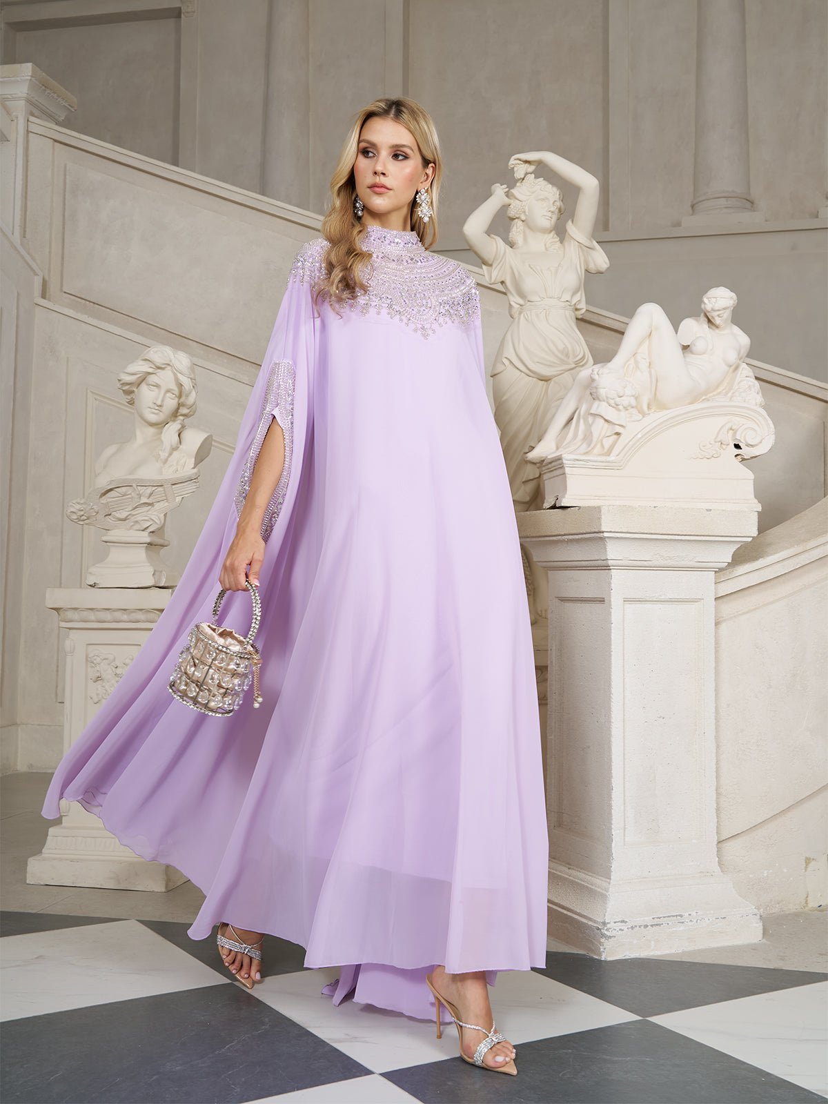 A woman in a flowing lavender gown with lace details walks past white classical statues on a grand staircase, holding a small decorative handbag.