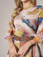 A woman wears a pleated, multicolored floral long-sleeve dress styled with the Social Queen Bohemian Laser-Cut Leather Belt, plus a gold necklace and earrings. Her face is not visible.