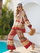 A woman walks by a pool wearing sunglasses, heeled sandals, and the Social Queen Bohemian Print Silk Scarf, paired with loose-fitting clothes and a bamboo handbag. Lush plants and white walls are in the background.